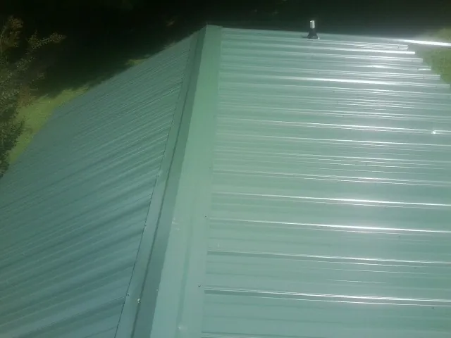 New green metal panels meeting at the ridge of a roof — Flat Roof Repair work by our crew in Mission Viejo