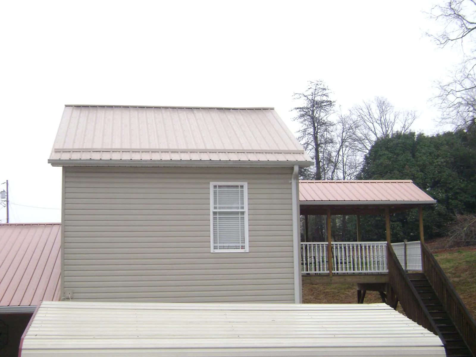 Tan metal roofs on a two story addition and attached porch, from a Roof Replacement job in Mission Viejo