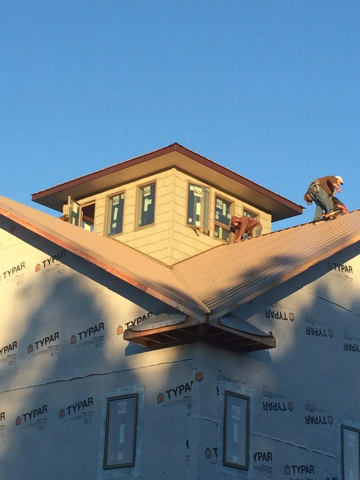 Roofers working around a rooftop cupola on a new metal roof at sunset — Roof Waterproofing in Mission Viejo by Roofing Brothers